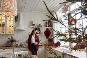 A pregnant woman stands in the kitchen, which is decorated for the holidays
